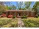 Charming brick home featuring a well-manicured lawn, mature trees, and beautiful flowering bushes at 3126 Truitt Dr, Burlington, NC 27215