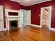 Bedroom featuring a fireplace, hardwood floors, red paint, and access to other rooms at 330 W King St, Hillsborough, NC 27278