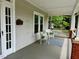 Cozy covered porch with white wicker furniture and a striped rug at 330 W King St, Hillsborough, NC 27278
