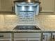 Close-up of a modern cooktop with granite countertops, white cabinets, and stylish subway tile backsplash at 335 Gwendolyn Way, Fuquay Varina, NC 27526