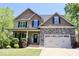 Charming two-story home featuring stone accents, a covered porch, and an attached two-car garage at 335 Gwendolyn Way, Fuquay Varina, NC 27526