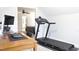 Bright home office featuring a treadmill and desk area near a view into the main bedroom at 335 Gwendolyn Way, Fuquay Varina, NC 27526
