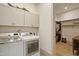 Well-lit laundry room with front-loading washer and dryer, storage cabinets, and access to the walk-in closet at 337 Sunset Hill Ln, Wendell, NC 27591