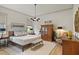 Bright main bedroom featuring a wooden bed frame, white blanket, sitting bench, and light hardwood floors at 337 Sunset Hill Ln, Wendell, NC 27591