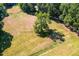 Aerial view of large grassy lot with mature trees and white fence and horse enclosure at 3521 Banks Rd, Raleigh, NC 27603