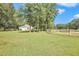 Spacious backyard with green grass, mature trees, and a white house in the background at 3521 Banks Rd, Raleigh, NC 27603