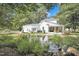 Expansive backyard with a serene pond, lush greenery, and a charming home with covered porches at 3521 Banks Rd, Raleigh, NC 27603