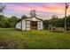 Rustic barn with an open doorway surrounded by green grass and trees at sunset at 3521 Banks Rd, Raleigh, NC 27603