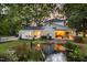 Exterior evening view of a beautiful white home with pond and string lights at 3521 Banks Rd, Raleigh, NC 27603