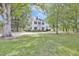 Spacious green lawn surrounds this two-story home in an idyllic landscape of lush trees at 3521 Banks Rd, Raleigh, NC 27603