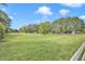 Expansive grassy land featuring a white fence border and scattered trees under a bright blue sky at 3521 Banks Rd, Raleigh, NC 27603