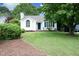Beautiful white home with green lawn, mature trees, blue door and shutters providing great curb appeal at 3521 Piedmont Dr, Raleigh, NC 27604