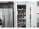 Well-organized pantry with wire shelving, a variety of food items, and stainless-steel refrigerator at 39 Principal Way, Clayton, NC 27520