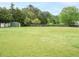 View of a large, grassy backyard featuring a shed and a wooden fence at 4501 Forest Dr, Holly Springs, NC 27540