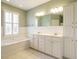Bright bathroom featuring double vanities, tiled floor, and separate tub at 4501 Forest Dr, Holly Springs, NC 27540