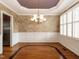 Formal dining room with a tray ceiling, a chandelier, wainscoting, and hardwood flooring at 4501 Forest Dr, Holly Springs, NC 27540