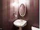 Chic powder room with stylish striped walls and a decorative oval mirror at 4501 Forest Dr, Holly Springs, NC 27540