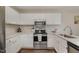 Well-lit kitchen with white cabinets, quartz countertops, and stainless steel appliances is move-in ready at 48 Fashion Pl, Durham, NC 27705