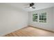 This bedroom has wood-look floors, a modern ceiling fan, and a window with views of lush greenery at 6421 Arrington Rd, Raleigh, NC 27607
