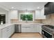 Bright kitchen with white cabinets, stainless steel appliances, quartz countertops and a view of nature at 6421 Arrington Rd, Raleigh, NC 27607