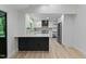 Open-concept kitchen features white cabinets, stainless steel appliances, a modern island, and wood-look floors at 6421 Arrington Rd, Raleigh, NC 27607
