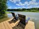 Scenic view of two black Adirondack chairs overlooking a lake on a wooden dock at 665 Lonach Ln, Roxboro, NC 27574