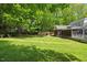Expansive backyard featuring lush green grass, mature trees, and a screened-in porch for outdoor enjoyment at 6819 Rainwater Rd, Raleigh, NC 27615