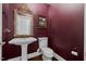 Stylish powder room with elegant mirror, pedestal sink, and rich, dark walls at 6819 Rainwater Rd, Raleigh, NC 27615