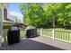 Outdoor deck with grills, white railing, and view of tree-lined backyard at 6819 Rainwater Rd, Raleigh, NC 27615