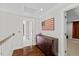 Upper hallway with hardwood floors, wood trim, dark dresser, and an American flag art piece at 6819 Rainwater Rd, Raleigh, NC 27615