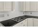 Close up of kitchen with gas cooktop, white subway tile, and sleek black countertops at 6819 Rainwater Rd, Raleigh, NC 27615