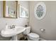 Half bath with pedestal sink, decorative mirror and a stained-glass window at 7420 Heartland Dr, Wake Forest, NC 27587