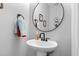 Modern bathroom showcasing a round mirror and a pedestal sink with stylish fixtures at 7829 Acc Blvd, Raleigh, NC 27617