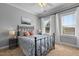 Bedroom featuring an iron bed frame, ceiling fan, and large windows providing ample sunlight at 7829 Acc Blvd, Raleigh, NC 27617