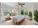 Inviting bedroom with a queen-sized bed, ceiling fan, and windows overlooking lush greenery at 7851 Allscott Way, Raleigh, NC 27612