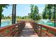 Scenic view of a wooden pier extending over a tranquil pond with a fountain and well-maintained landscaping nearby at 825 Flower Manor Dr, Wendell, NC 27591