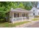 Charming home featuring a cozy front porch, neutral siding, dark shutters, and mature landscaping at 919 Orient St, Durham, NC 27701