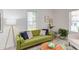 Comfortable living room featuring green sofa, wood coffee table, and neutral decor, filled with light at 919 Orient St, Durham, NC 27701
