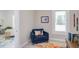 Cozy sitting area with a blue armchair, colorful pillow, and bright window at 919 Orient St, Durham, NC 27701