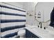 Stylish bathroom featuring a blue vanity, white countertop, patterned wallpaper, and a shower with a striped curtain at 1010 Smoke Willow Way, Rolesville, NC 27571