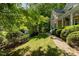 Well-manicured lawn with lush green grass, mature trees, flowering bushes, and brick pathway at 102 Treadwell Ct, Cary, NC 27513