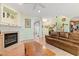 Open-concept living room with a fireplace, hardwood floors, arched doorway, and a comfortable leather couch at 102 Treadwell Ct, Cary, NC 27513