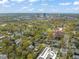 This aerial shows an overview of a neighborhood with houses, businesses, trees and city in the distance at 1024 W Markham Ave, Durham, NC 27701