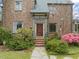 An inviting brick home featuring a classic front door, well maintained lawn, and beautiful flowering bushes in the yard at 1024 W Markham Ave, Durham, NC 27701