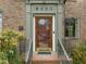 Classic brick home entrance featuring a wood and glass front door, with a historic building plaque, and professional landscaping at 1024 W Markham Ave, Durham, NC 27701