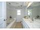 Well-lit bathroom features neutral tile, vanity with stone countertop, and a tub with tiled surround at 104 Silver Fox Ct, Cary, NC 27511