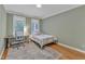 Bright bedroom featuring a single bed, wood floors, a study desk, and two windows at 106 Kenneil Ct, Apex, NC 27502