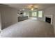 Living room with kitchen view, fireplace, and large windows offering ample natural light at 115 Oakfield Trace Dr, Four Oaks, NC 27524