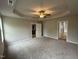 Large main bedroom featuring tray ceiling with fan, neutral walls, and ensuite bath and kitchen access at 115 Oakfield Trace Dr, Four Oaks, NC 27524