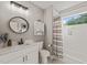 Bathroom featuring a round mirror above a white sink and a shower and tub combination at 1202 S Bloodworth St, Raleigh, NC 27601